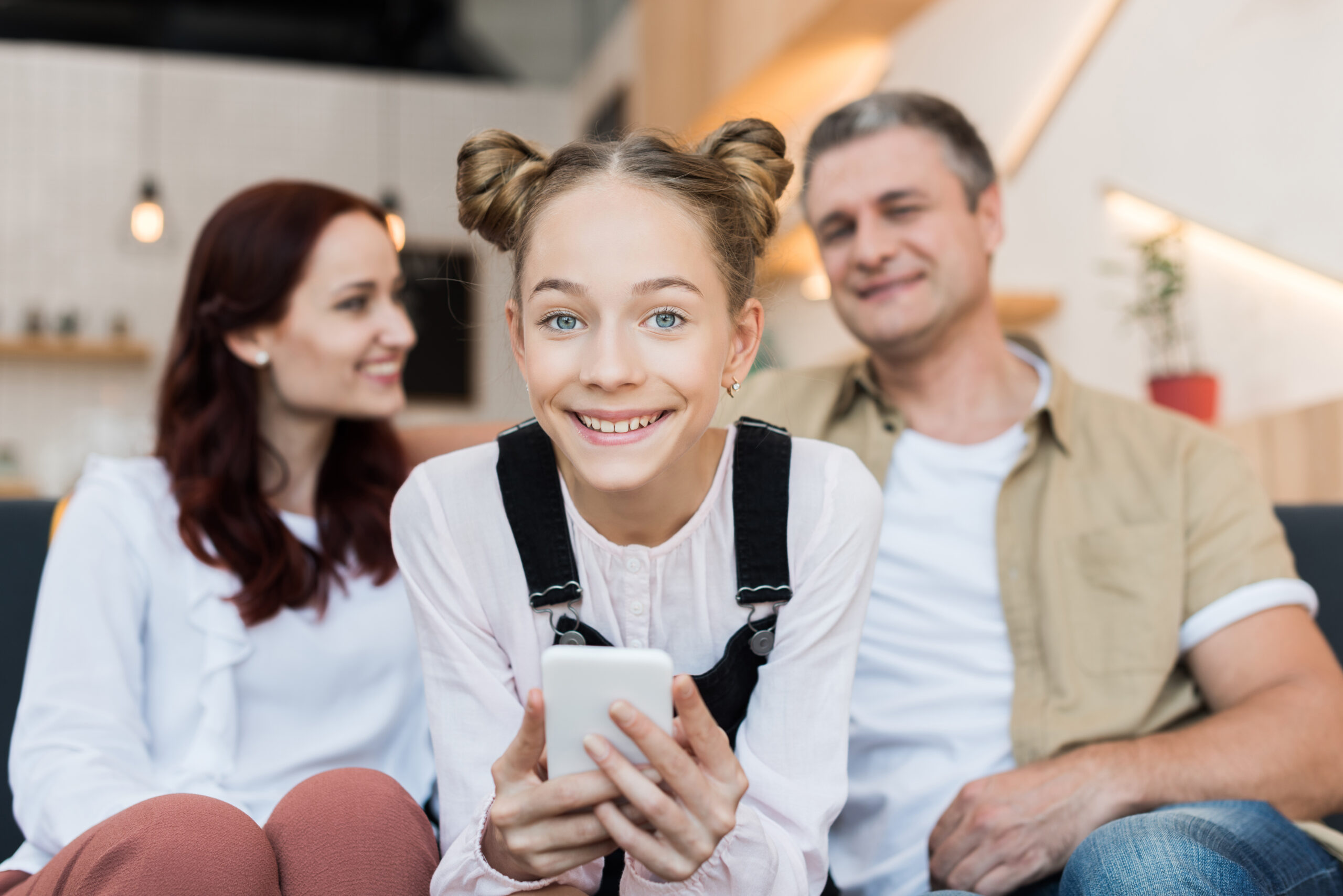 mature parents and teen girl with smartphone